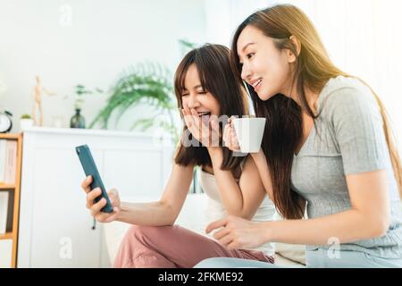 Two roommates using their smart phones  sitting on a sofa  at home Stock Photo