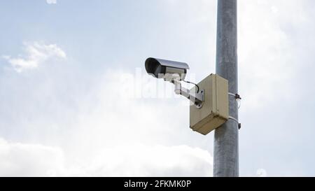 Surveillance camera mounted on a pole with sky background Stock Photo