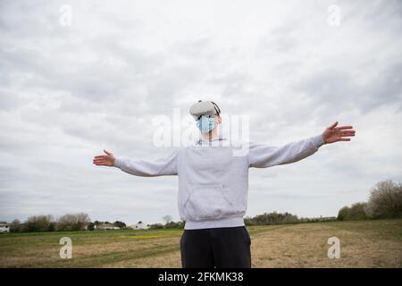 A man has fun using a virtual reality headset outdoors in a field Stock Photo