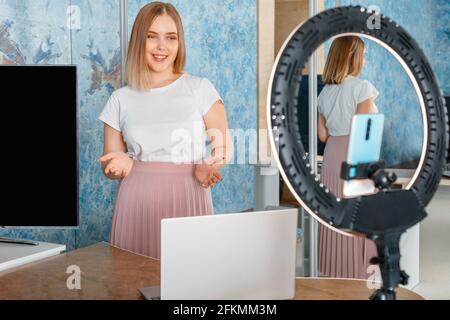 Online teacher records video lessons. Manager do presentation during online meeting. Woman record stream using laptop smartphone ring lamp. Coach Stock Photo