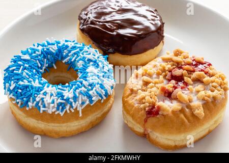 Donuts with different toppings on white plate. Stock Photo