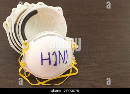 Close up of white mask stack  and word H1N1 in mask on black wooden  background,touch-up in prevention of influenza Stock Photo