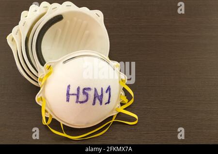 Close up of white mask stack  and word H1N1 in mask on black wooden  background,touch-up in prevention of influenza Stock Photo