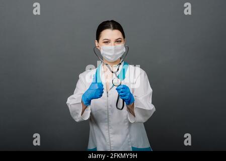 Beautiful female doctor in protective mask looking away and thinking about something. Stock Photo