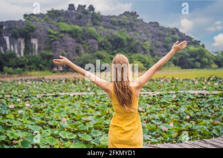 Young woman in a yellow dress on the path among the lotus lake. Mua Cave, Ninh Binh, Vietnam. Vietnam reopens after quarantine Coronovirus COVID 19 Stock Photo