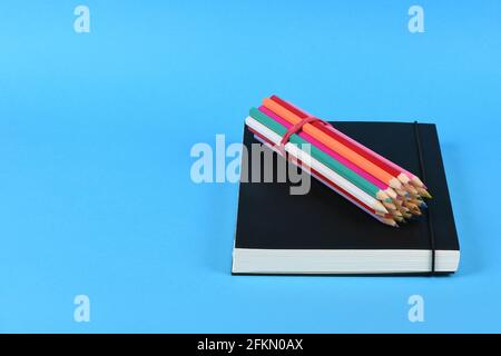 Side view of workplace with pencils on notebook on blue background. High resolution photo. Full depth of field. Stock Photo