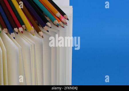 Side view of workplace with pencils on notebook on blue background. High resolution photo. Full depth of field. Stock Photo