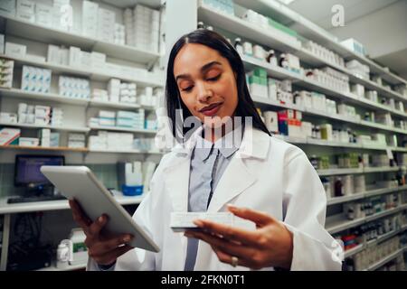 Female african american pharmacist working in chemist checking medicine details in digital tablet Stock Photo