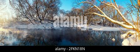 Frosty winter panoramic landscape with forest river during sunny january morning.
