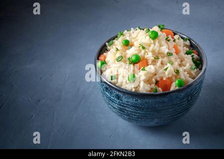 Rice with green peas, carrots, and scallions, on a dark blue background with a place for text Stock Photo