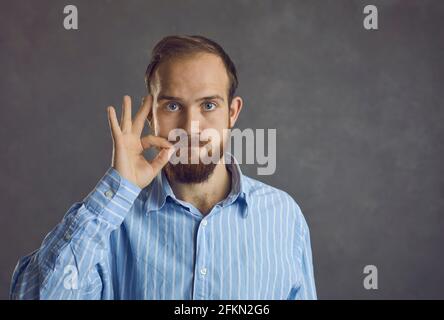 Portrait of brutal bearded hipster man twist mustache stand on grey studio wall Stock Photo