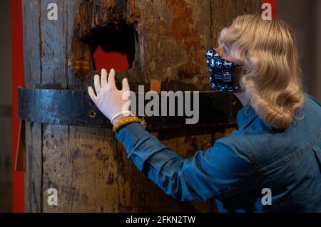 Alice Roberts-Pratt, Interpretation Officer at the National Museum of the Royal Navy, studies a section of the original wooden foremast from HMS Victory with a hole in the middle made by a cannon ball during the Battle of Trafalgar. The piece has been lent by Queen Elizabeth II from the Royal Collection and is one of the main exhibits on display in the new HMS Victory: The Nation's Flagship gallery at Portsmouth Historic Dockyard, which will open to the public on May 17th. Picture date: Friday April 30, 2021. Stock Photo