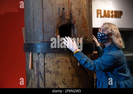 Alice Roberts-Pratt, Interpretation Officer at the National Museum of the Royal Navy, studies a section of the original wooden foremast from HMS Victory with a hole in the middle made by a cannon ball during the Battle of Trafalgar. The piece has been lent by Queen Elizabeth II from the Royal Collection and is one of the main exhibits on display in the new HMS Victory: The Nation's Flagship gallery at Portsmouth Historic Dockyard, which will open to the public on May 17th. Picture date: Friday April 30, 2021. Stock Photo