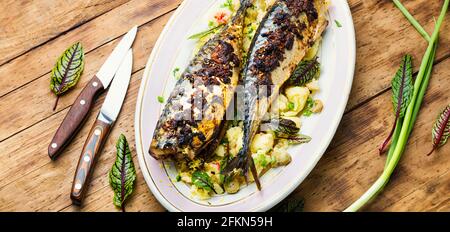 Roasted mackerel with boiled potatoes.Baked scomber with green on wooden table Stock Photo