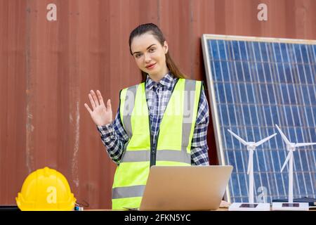 factory workers or engineers holding light bulb and using tablet computer with windmill model on solar panel,  work in containers warehouse storage Stock Photo