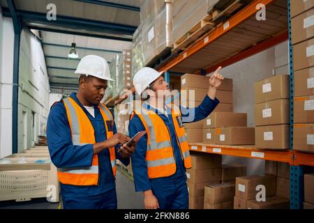 Two multiracial male workers working together in a manufacturing plant Stock Photo