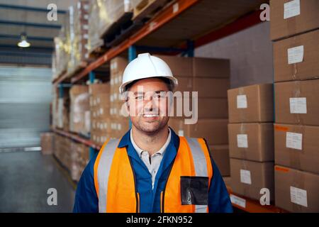 Portrait of a smiling industrial male worker standing in warehouse looking at camera Stock Photo