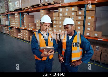 Two industrial workers discussing project work in large industrial plants with digital tablet Stock Photo