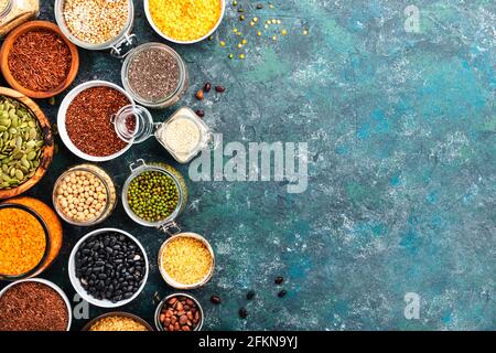 Various organic superfoods, beans, grains, cereals, legumes, seeds in reusable cans and jars. Copy space top view. Blue background Stock Photo