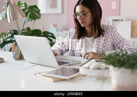 Indian mixed-race beautiful businesswoman working on a new project on her workplace using laptop at the office. Stock Photo