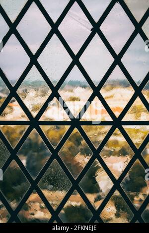 window with a rusty grille with a wrought iron pattern Stock Photo