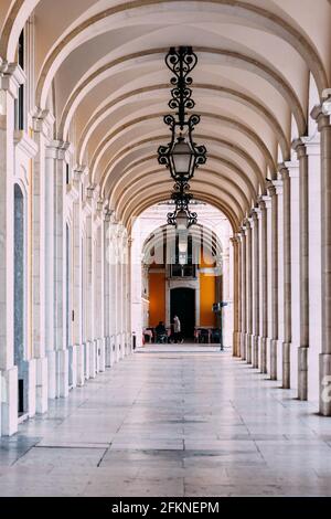 Detail of ana arcade surrounding praca do comercio in Lisbon, Portugal. Older man with face mask is visible in background Stock Photo