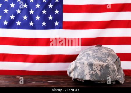 US Army kevlar combat helmet, camo cover, tactical goggles, USA flag background. Memorial weekend, veterans day, United States of America armed forces Stock Photo