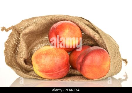 Several juicy organic nectarines in a jute bag, close-up, isolated on white. Stock Photo