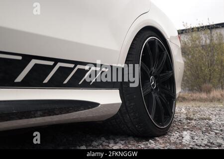 The Rear Gloss Black Alloy Wheel On A 2013 Mercedes Benz E63s AMG W212 Saloon In White With Black AMG Side Stripes Stock Photo