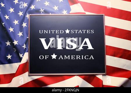 Close up of black chalkboard with UNITED STATES OF AMERICA VISA text written on it. Visa application formalization concept. Ruffled USA American flag Stock Photo