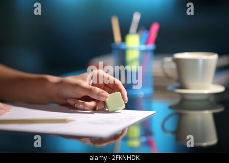 Close up of a woman hand erasing with an eraser in the night at home Stock Photo