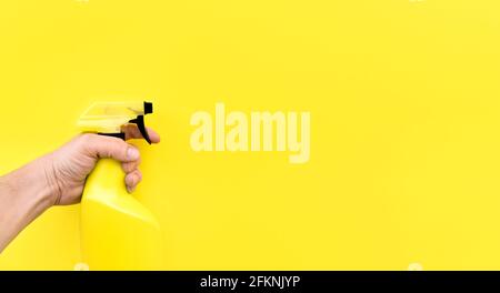 Close up of person's hand with cleaning sprayer isolated on yellow background. Space for text. Stock Photo