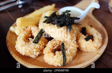 Deep fried squid rings on wooden plate Stock Photo