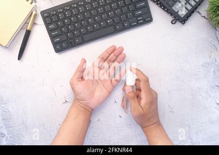 young man hand using hand sanitizer spray on office desk Stock Photo