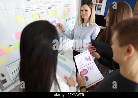 Woman coach explaining information at blackboard group of students Stock Photo