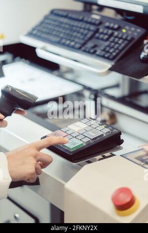 Factory worker pressing the OK button on a machine Stock Photo