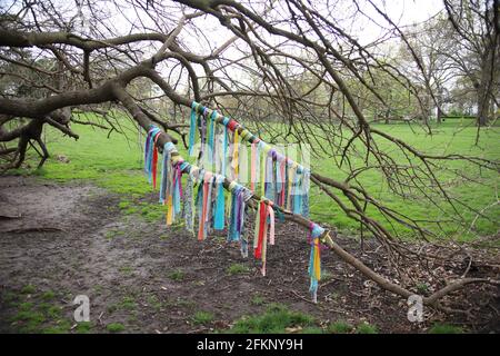 Closeup of colorful napkins on a wish tree in a garden under a cloudy sky
