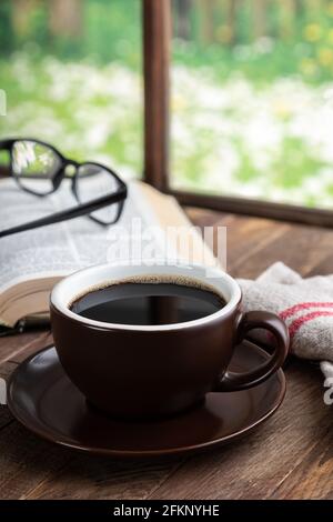Cup of coffee and book on wooden table with rural background scene Stock Photo