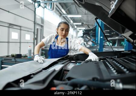 Female mechanic checks engine, car service Stock Photo