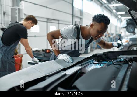 Two male mechanics inspects engine, car service Stock Photo