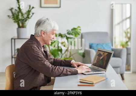 Side view portrait of mature man speaking by video chat with son at graduation Stock Photo