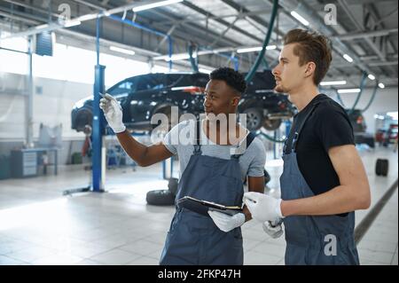 Two male mechanics talking in car service Stock Photo