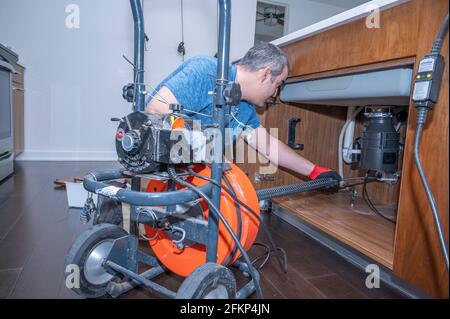 Plumber drain cleaning a kitchen sink inside a residential home Stock Photo