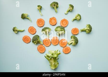 Vegan food concept. Explosion of carrots and broccoli on blue background. Top view. High quality photo Stock Photo