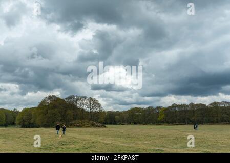 Chorleywood, UK.  3 May 2021.  UK Weather: People walking under ominous grey clouds gathering over Chorleywood Common, Hertfordshire on May’s early Bank Holiday Monday.  The forecast is for conditions to worsen with heavy rain and strong winds towards the end of the day.  Credit: Stephen Chung / Alamy Live News Stock Photo