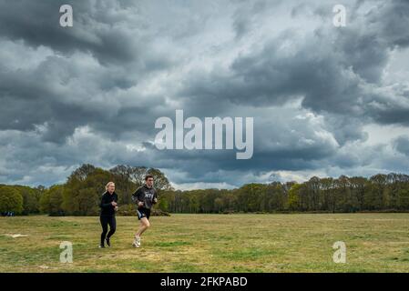 Chorleywood, UK.  3 May 2021.  UK Weather: A couple out for a run under ominous grey clouds gathering over Chorleywood Common, Hertfordshire on May’s early Bank Holiday Monday.  The forecast is for conditions to worsen with heavy rain and strong winds towards the end of the day.  Credit: Stephen Chung / Alamy Live News Stock Photo