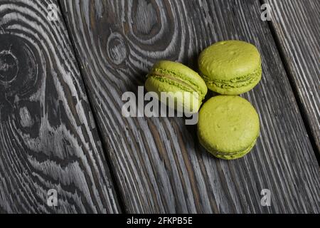 Macarons cakes light green color. They lie on black and white pine boards. Stock Photo