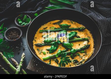 Omelette with green asparagus, basil and herbs on black background Stock Photo