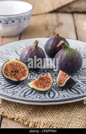 Figs on a blue and white patterned plate on rustic jute and wood Stock Photo