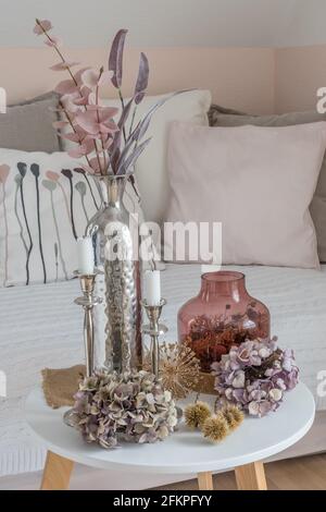 Beautiful harmonious autumn decoration on coffee table with dried hydrangea flowers, chestnut bowls, pink glass vase, pink and purple branches and whi Stock Photo